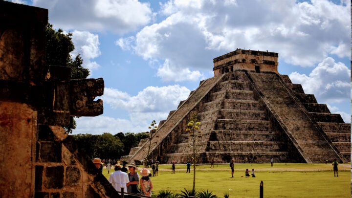 Visitors exploring the ancient ruins of Chichen Itza, a UNESCO World Heritage site, with a knowledgeable guide by Carey Tours.
