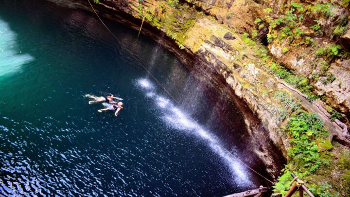 Swimming in a serene cenote surrounded by lush greenery, showcasing a tranquil escape in Tulum by Carey Tours