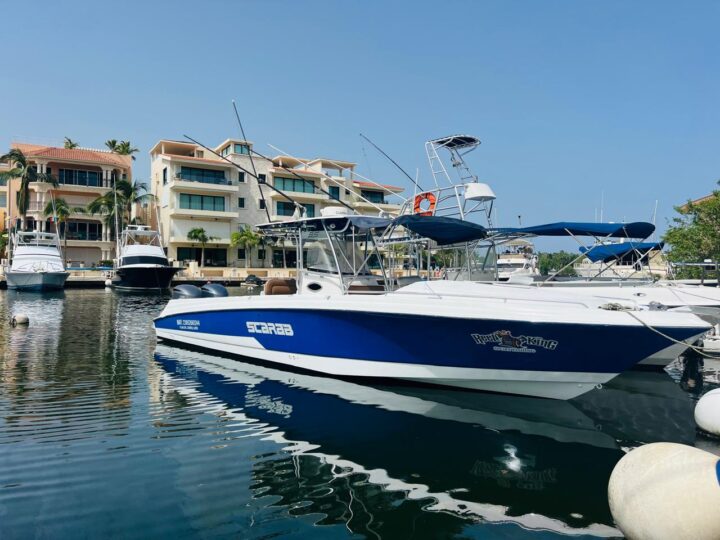 Sport fishing boat moored at a tranquil marina near Playa del Carmen, showcasing local architecture, by Carey Tours.