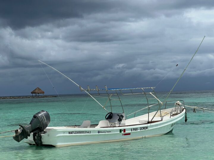 A boat anchored in tranquil waters off the coast of Cancun, perfect for a private tour experience by Carey Tours.