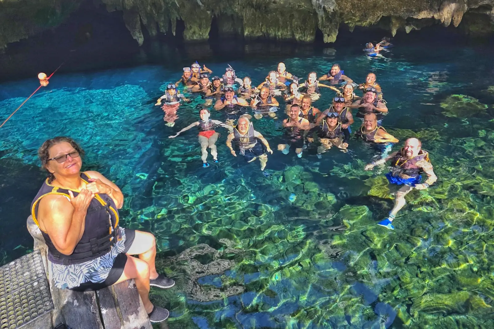 Group of travelers enjoying a refreshing swim in a cenote surrounded by lush greenery during a private tour by Carey Tours.