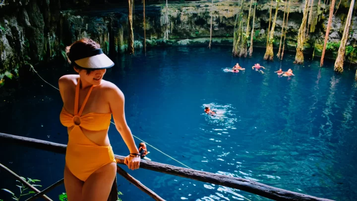 Relaxing moment by a crystal-clear cenote in Tulum, with guests swimming and enjoying nature, provided by Carey Tours.
