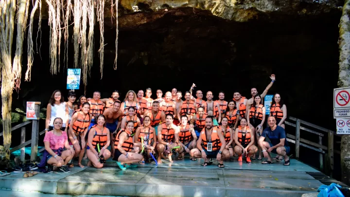 Group enjoying a private tour at a cenote, adorned in life jackets, surrounded by lush jungle scenery, by Carey Tours.