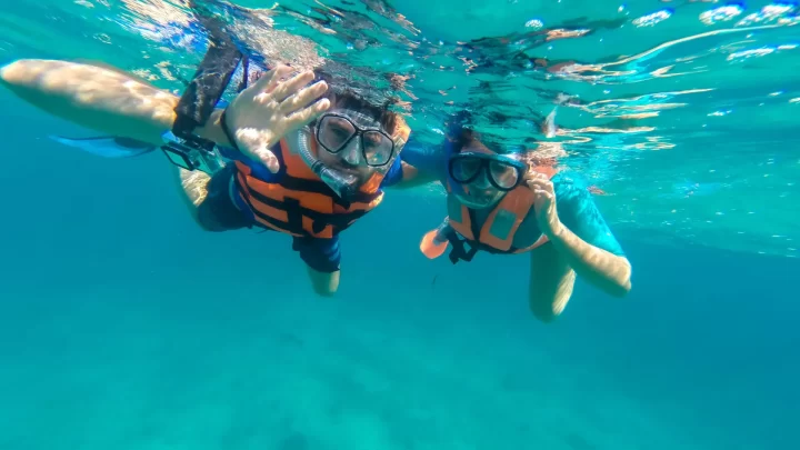 Snorkeling in the vibrant waters of a Tulum lagoon, two guests enjoying a serene experience surrounded by marine life by Carey Tours