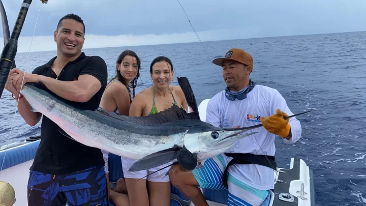 Group of friends celebrating a successful fishing trip, holding a large marlin in the Caribbean Sea, captured during a tour by Carey Tours.