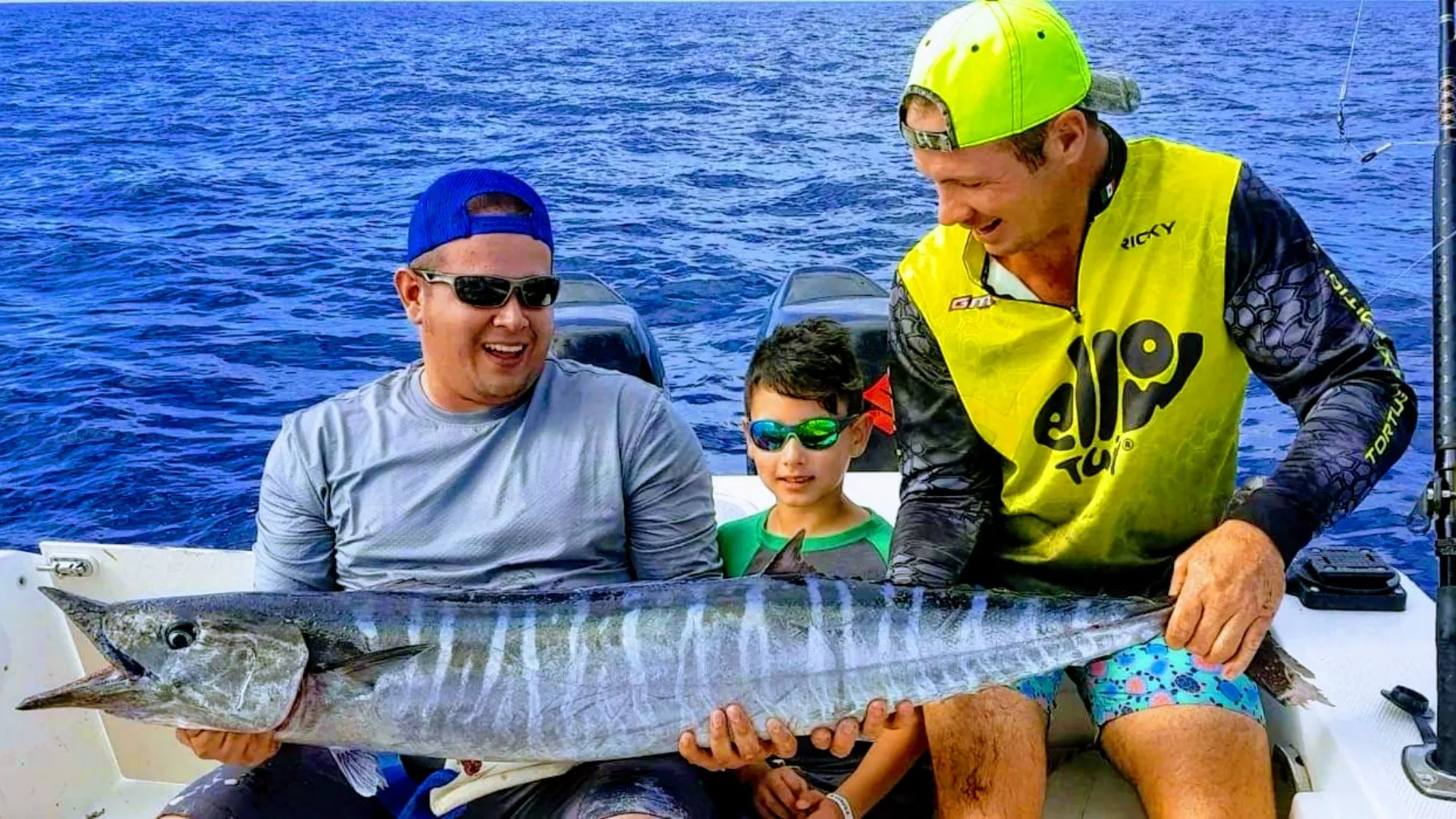 Family enjoys deep-sea fishing on a private tour, proudly displaying their catch against the vibrant backdrop of the Caribbean Sea by Carey Tours.