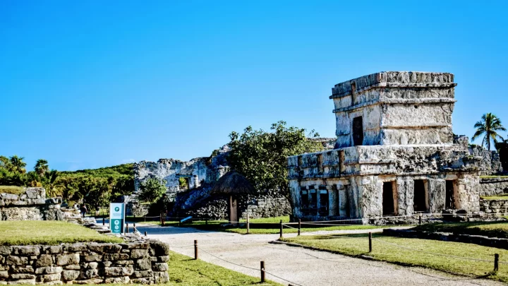 Ancient ruins surrounded by lush greenery at Tulum, providing a serene atmosphere during a private tour by Carey Tours.