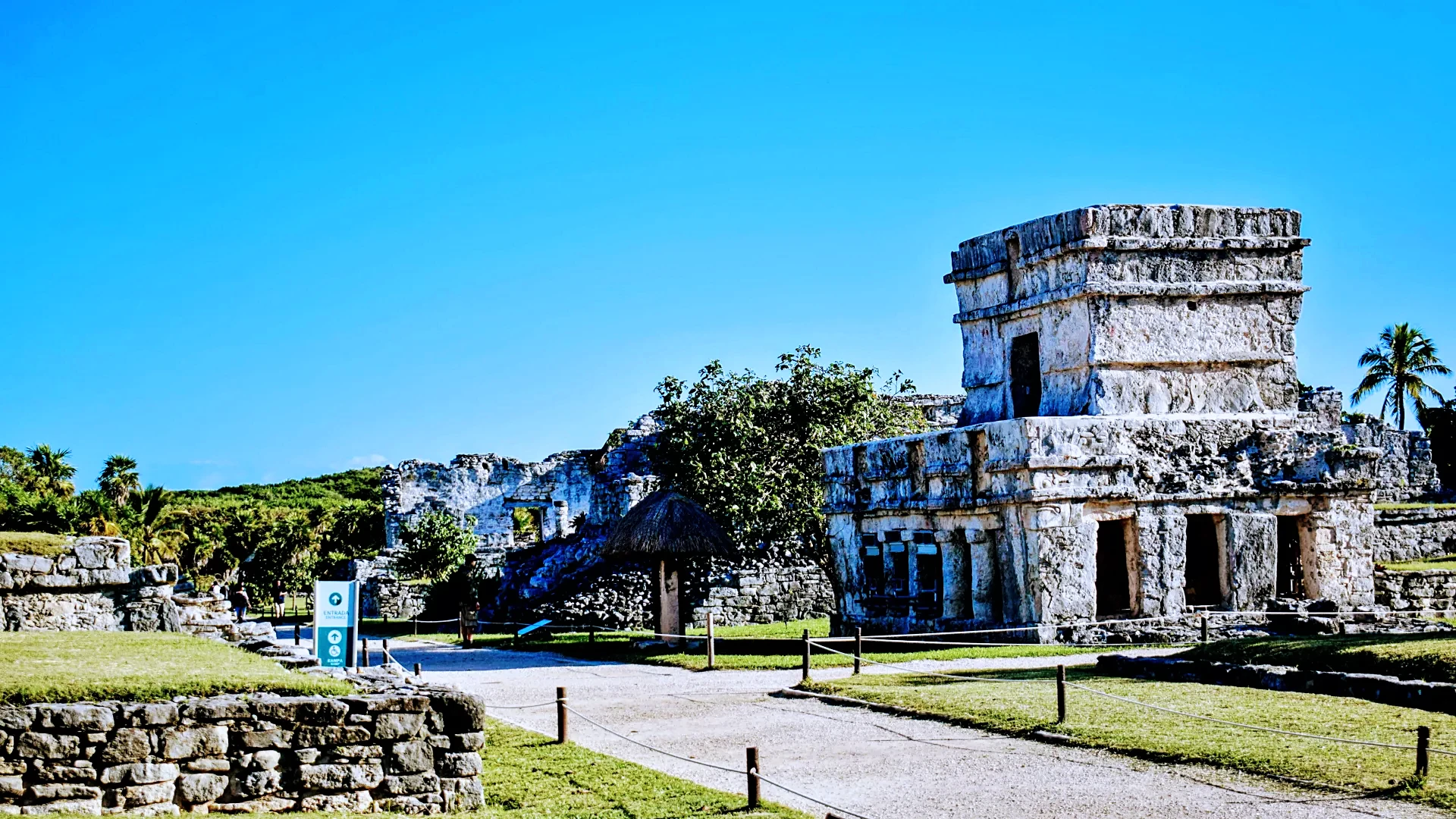 Archaeological site of Tulum showcasing ancient ruins set against a clear blue sky, highlighting the history and beauty by Carey Tours.