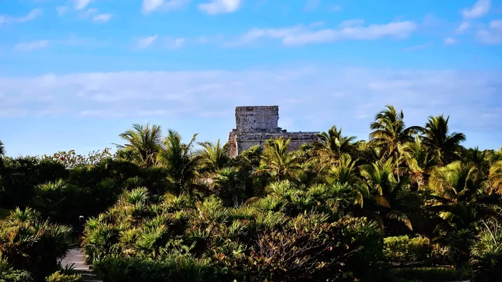 Ancient ruins of Tulum rising above lush tropical vegetation, showcasing the beauty of the archaeological site by Carey Tours
