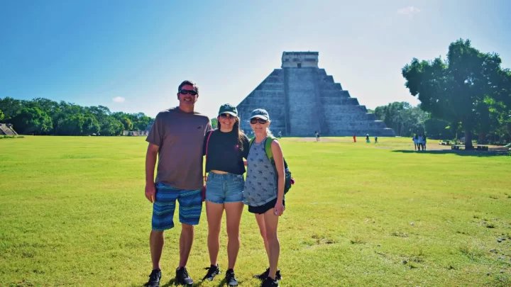 Visitors exploring the archaeological site of Tulum, capturing the serene atmosphere and ancient ruins by Carey Tours.