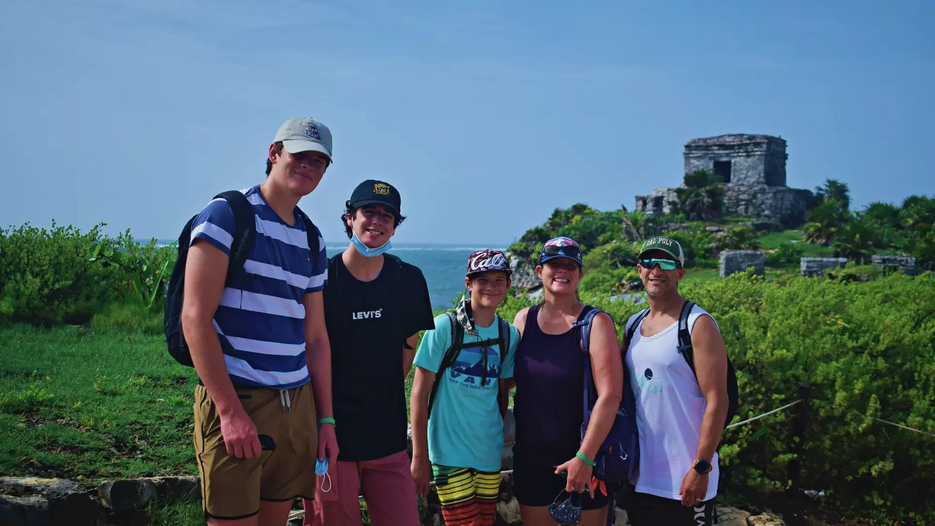 Group of visitors exploring the Tulum archaeological site, surrounded by lush greenery, with a local guide by Carey Tours.