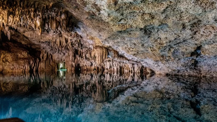 Serene underground cenote in Tulum, reflecting natural rock formations and crystal-clear water during a private tour by Carey Tours.